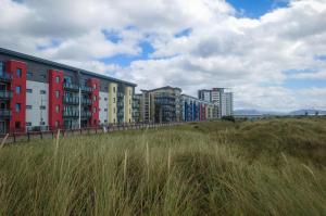 a row of buildings on a beach with tall grass at Maritime Quarter - 2 Bedroom Apartment - SA1 Beach Front Fishermans Way in Swansea
