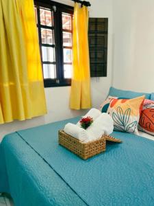 Una cama con toallas y una cesta. en Pousada Harmonia en Tamandaré