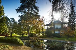 a house in a park with a pond and trees at Fanhams Hall, Exclusive Collection in Ware