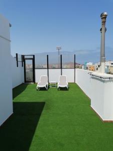 balcón con 2 sillas y césped verde en Apartamentos Risco Verde, en Arinaga