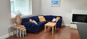 ein Wohnzimmer mit einem blauen Sofa und einem TV in der Unterkunft Carraroe Apartment 2 in Carraroe