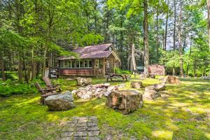a log cabin in the middle of a yard with rocks at Secluded and Quiet Pocono Mountain Cabin with Hot Tub! in Kunkletown