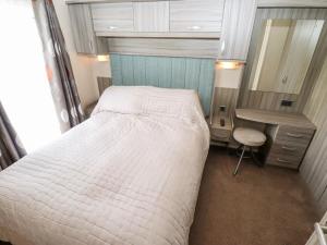 a bedroom with a bed and a desk and a mirror at 19 The Brambles in Humberston