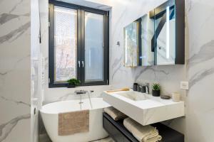 La salle de bains est pourvue d'un lavabo blanc et d'un miroir. dans l'établissement Ravissant loft avec vue sur Seine, à Courbevoie