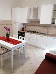 a kitchen with white cabinets and a white table with purple flowers at IN CENTRO in Porto SantʼElpidio +10 photos