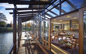 a restaurant with tables and chairs next to the water at Fanhams Hall, Exclusive Collection in Ware