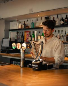 a man standing behind a bar with a juicer at Ballinluig Rooms & Suites in Pitlochry