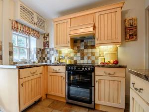 a kitchen with wooden cabinets and a stove top oven at Peak Cottage in Bakewell