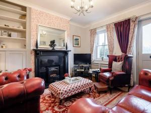 a living room with leather furniture and a fireplace at Peak Cottage in Bakewell