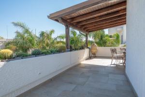 un patio con pérgola de madera, mesa y sillas en CasaRizzo en Torre dell'Orso