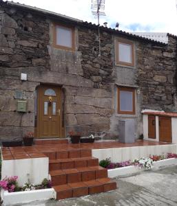 a stone house with a wooden door and stairs at Casa Malvina in A Coruña
