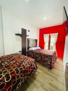 2 Betten in einem Zimmer mit einem Kreuz an der Wand in der Unterkunft HOTEL LA GRAN MANZANA in Zacatlán