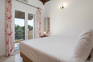 a white bedroom with a bed and a balcony at Casa Callianeira Residence in Tsilivi