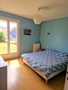 a bedroom with a blue wall and a blue bed at À 10 minutes de voiture d'Étretat in Les Loges
