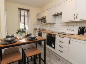 a kitchen with white cabinets and a wooden table at 45 Prince Street in Keighley