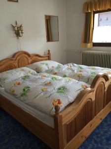 ein Holzbett mit einer Decke mit Blumen darauf in der Unterkunft Pension Brixen im Thale in Brixen im Thale