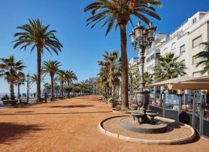 una calle con palmeras y una fuente en una playa en AL36 - Apartamento de lujo a 100 metros de playa, en Lloret de Mar
