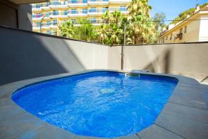 una gran piscina azul en la parte lateral de un edificio en AL36 - Apartamento de lujo a 100 metros de playa, en Lloret de Mar