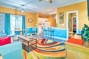 sala de estar y cocina con paredes amarillas y azules en Colorful Myrtle Beach Golf Club Condo with Pool en Myrtle Beach