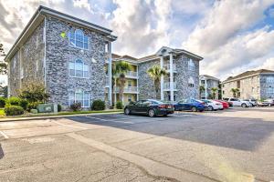 a large building with cars parked in a parking lot at Colorful Myrtle Beach Golf Club Condo with Pool in Myrtle Beach