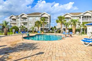 a large apartment building with a swimming pool and palm trees at Colorful Myrtle Beach Golf Club Condo with Pool in Myrtle Beach