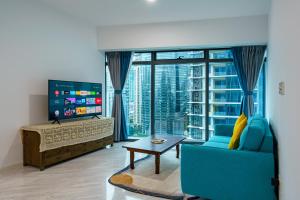 a living room with a blue couch and a large window at Eaton Residence KLCC in Kuala Lumpur