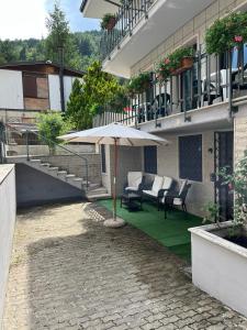 eine Terrasse mit einem Tisch, Stühlen und einem Sonnenschirm in der Unterkunft Petite Home in Roccaraso