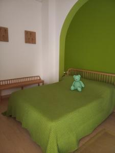 un lit vert avec un ours en peluche assis sur lui dans l'établissement Villa Annamaria - b&b, à Ballabio