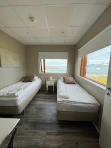 two beds in a room with a window at Við Hafið Guesthouse in Ólafsvík