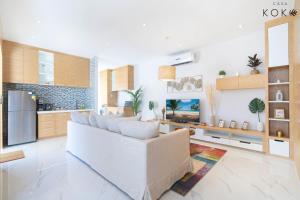 Villa Casa Koko Phuket - Stay in Style في تالانغ: غرفة معيشة مع أريكة بيضاء ومطبخ