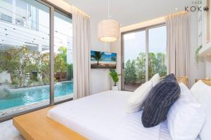Villa Casa Koko Phuket - Stay in Style في تالانغ: غرفة نوم بسرير ابيض ونافذة كبيرة