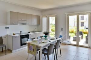 una cucina con tavolo e sedie e una cucina con armadietti bianchi di Hyele Accommodation Experience a Casal Velino