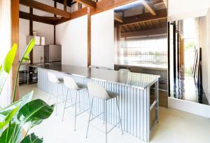 a kitchen with a bar with white chairs at Akizuki OKO art&inn in Asakura