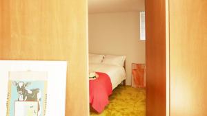 a small bedroom with a bed with a red blanket at Akizuki OKO art&inn in Asakura