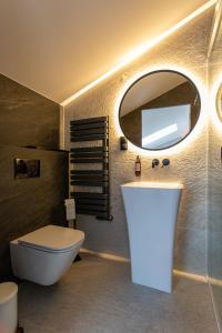 ein Badezimmer mit einem WC, einem Waschbecken und einem Spiegel in der Unterkunft Ogrodowa Premium in Gorlice