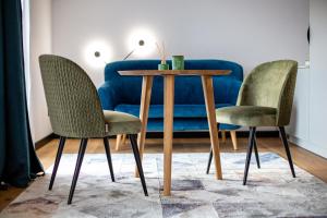 einen Tisch mit 2 Stühlen und eine blaue Couch in der Unterkunft Ogrodowa Premium in Gorlice