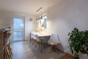 a dining room with a white table and chairs at Rekreačný domček Flower Garden - Self Check In in Dolný Kubín