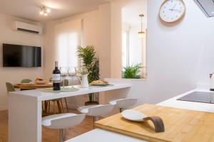 cocina y sala de estar con mesa y reloj en LUCIA DE TRIANA en Sevilla