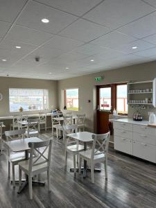 une salle à manger avec des tables et des chaises ainsi qu'une cuisine dans l'établissement Við Hafið Guesthouse, à Ólafsvík