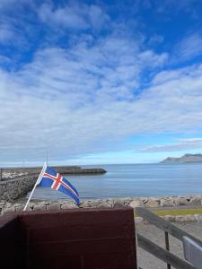 a flag sitting on top of a bench next to the water at Við Hafið Guesthouse in Ólafsvík