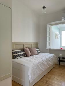 biała sypialnia z dużym łóżkiem z poduszkami w obiekcie Casa do Mercado w mieście Alcácer do Sal