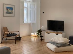 a living room with a flat screen tv on a white cabinet at Casa do Mercado in Alcácer do Sal