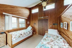 two beds in a room with wooden walls and windows at Duneshine #73-1 in Avon