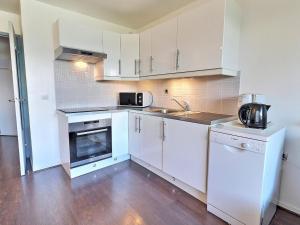 a kitchen with white cabinets and a sink and a microwave at Appartement La Tania, 2 pièces, 4 personnes - FR-1-182A-5 in Courchevel