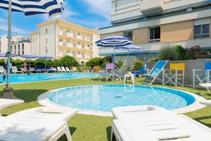 uma piscina com cadeiras e guarda-sóis num resort em Hotel Caesar em Cesenatico