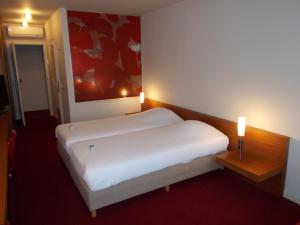 a bedroom with a white bed in a room at Hotel Corbie Lommel in Lommel