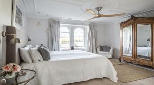 a white bedroom with a bed and a ceiling fan at Merchants House in Salcombe