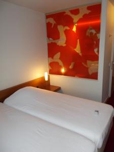 ein Schlafzimmer mit einem weißen Bett und einem Gemälde an der Wand in der Unterkunft Hotel Corbie Lommel in Lommel