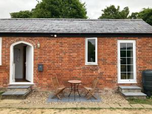 uma casa de tijolos com uma mesa e cadeiras em frente em Hunters Moon B&B em North Tidworth