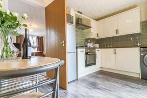 a kitchen with white cabinets and a vase of flowers at Delightful 2 Bed Room Property, Free Off Road Parking. in Cleethorpes